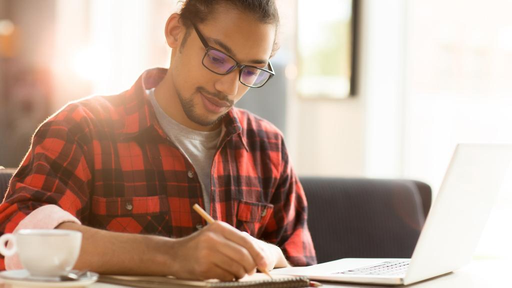 Young man writing notes on paper